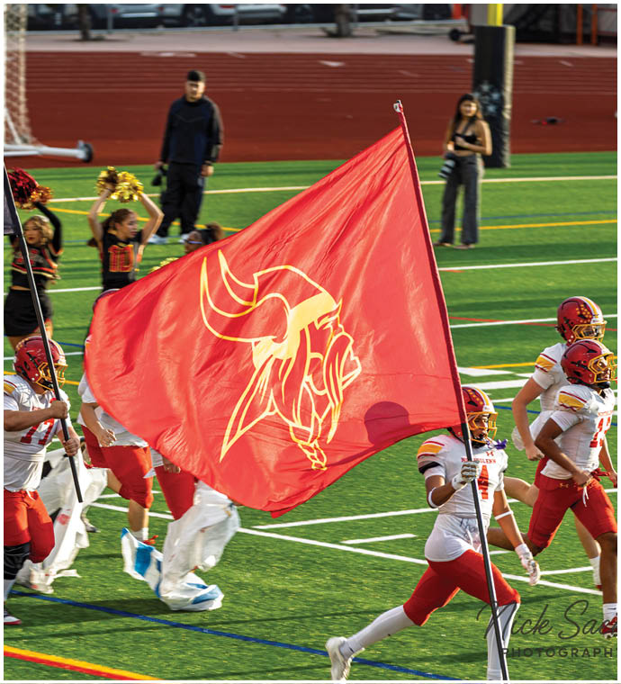A group of football players running on a field with red and white uniforms. Description generated by AI