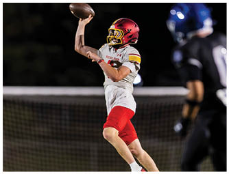A man wearing a white and red jersey is holding a football. Description generated by AI