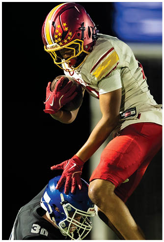 A football player in a red jersey is running with the ball. Description generated by AI