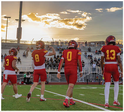 Three football players wearing red and white uniforms. Description generated by AI