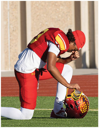 A football player wearing a red jersey with the number 3 on it. Description generated by AI