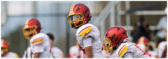 A group of football players wearing red and yellow jerseys. Description generated by AI