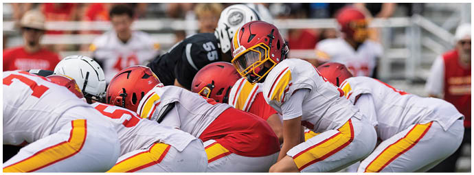 A group of football players in a huddle on the field. Description generated by AI