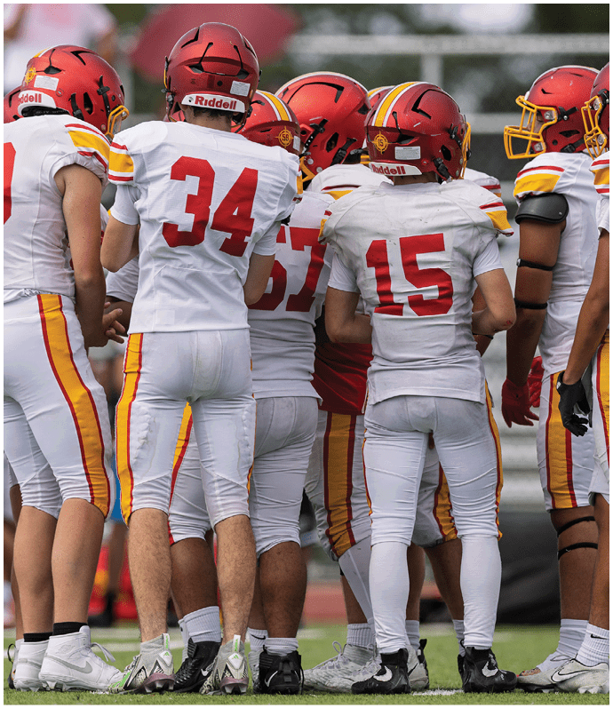 A group of football players wearing red and yellow jerseys. Description generated by AI