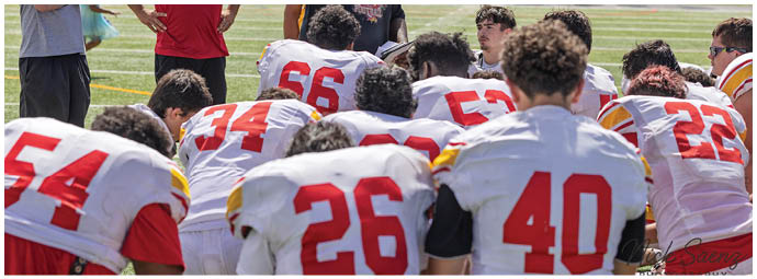 A group of football players kneeling on the field. Description generated by AI