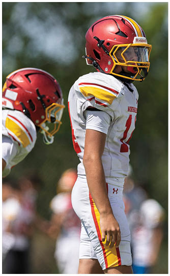 A football player wearing a red and yellow helmet. Description generated by AI