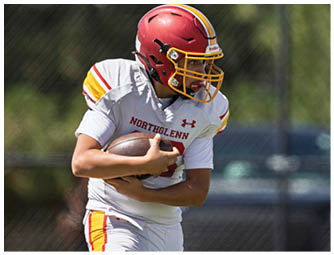 A boy wearing a white and red jersey is running with a football. Description generated by AI