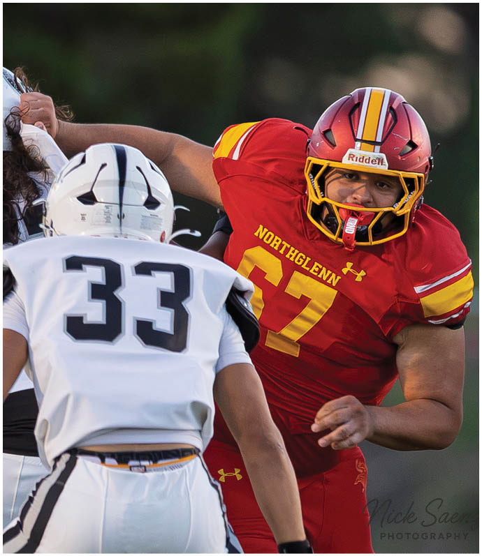 A football player wearing a red jersey with the number 77 on it. Description generated by AI