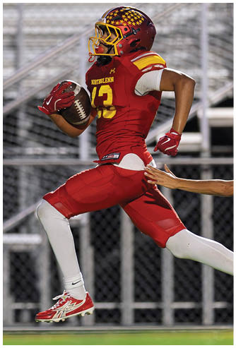 A football player wearing a red jersey with the number 21 running with the ball. Description generated by AI