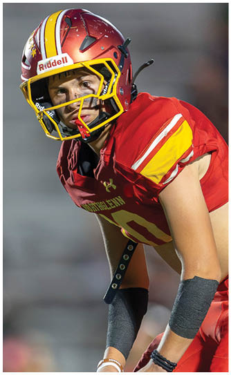 A football player wearing a red and yellow jersey. Description generated by AI
