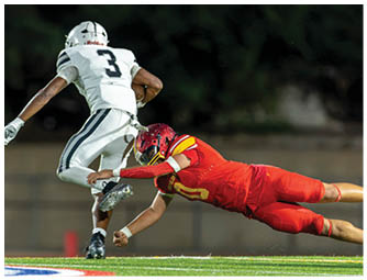 A football player in a red jersey is sliding on the ground. Description generated by AI