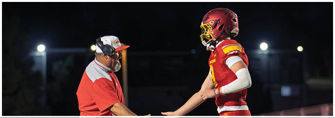Two men shaking hands on a football field. Description generated by AI