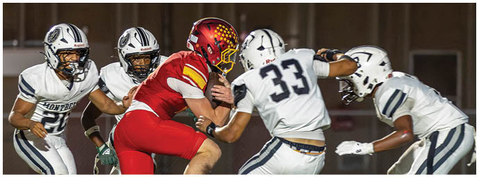 A football player in a red jersey is tackled by another player. Description generated by AI