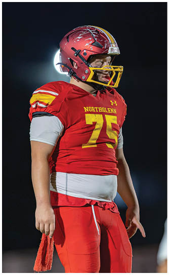 A football player wearing a red and yellow jersey with the number 74. Description generated by AI