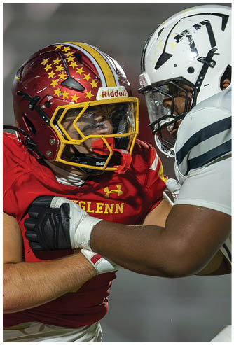 A football player wearing a red and yellow jersey is tackled by another player. Description generated by AI