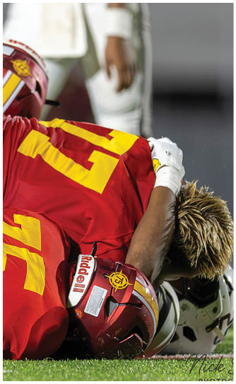 Two football players wearing red jerseys with the number 24 and 47 on them are laying on the ground. Description generated by AI