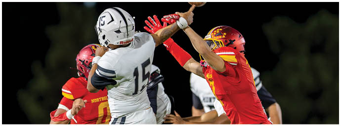 A football player in a red jersey is tackled by another player. Description generated by AI
