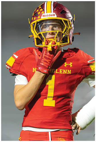 A football player in a red and yellow jersey is running with a football. Description generated by AI
