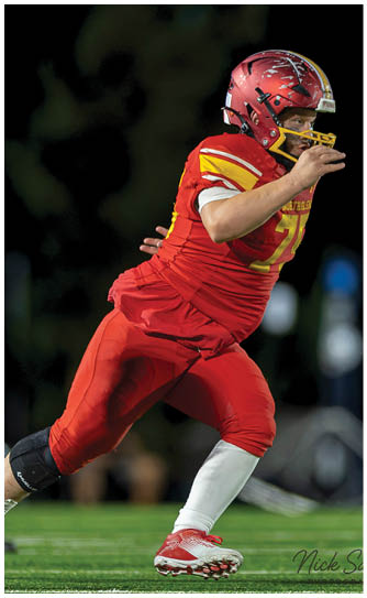 A football player wearing a red and yellow jersey with the number 74. Description generated by AI