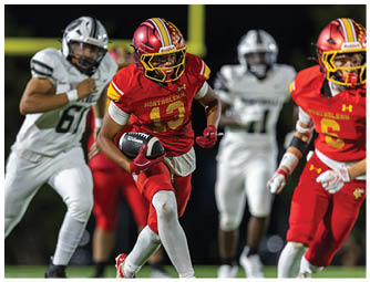 A football player in a red jersey is running with a football. Description generated by AI