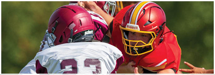 A football player in a red jersey is tackled by another player. Description generated by AI