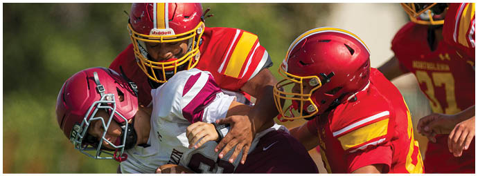 A group of young men playing football on a field. Description generated by AI