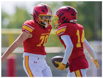 Two football players wearing red and yellow jerseys. Description generated by AI