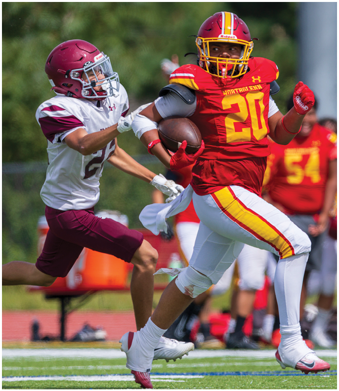 A football player in a red jersey running with a football. Description generated by AI