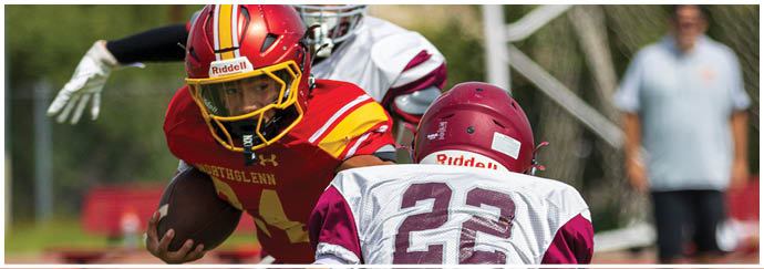 A football player in a red and yellow jersey running with a football. Description generated by AI