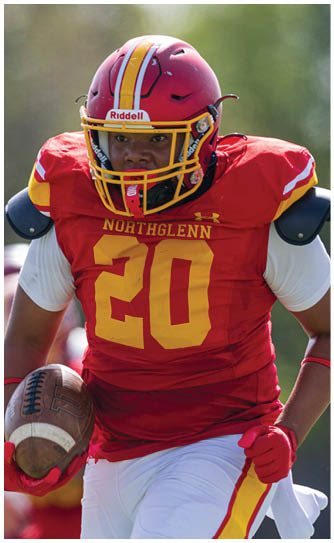 A football player wearing a red and yellow jersey with the number 20. Description generated by AI