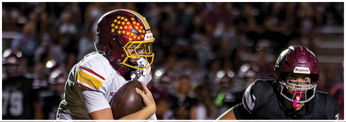 A football player in a white jersey with a red stripe is running with a football. Description generated by AI