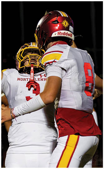 Two football players wearing white uniforms with red and yellow stripes. Description generated by AI