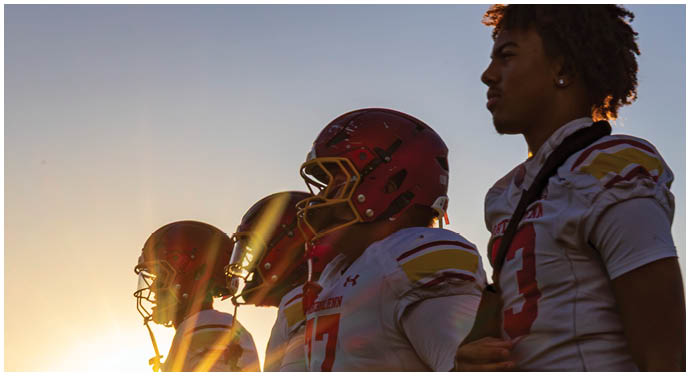 A group of football players standing on a field. Description generated by AI
