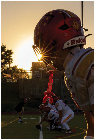 A football player wearing a red helmet with a white jersey. Description generated by AI
