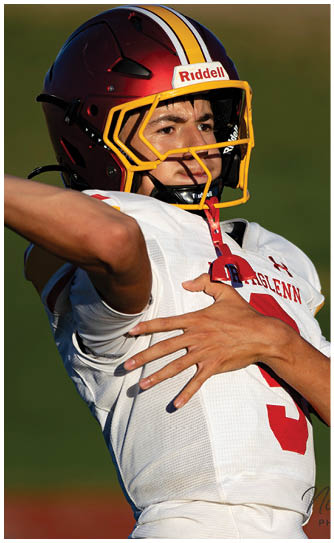 A man wearing a red and yellow helmet is holding a football. Description generated by AI