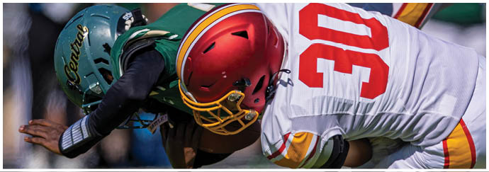 A football player in a red jersey is tackled by another player. Description generated by AI