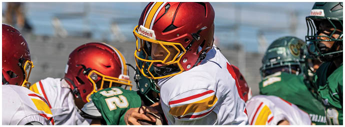 A group of young men playing football on a field. Description generated by AI