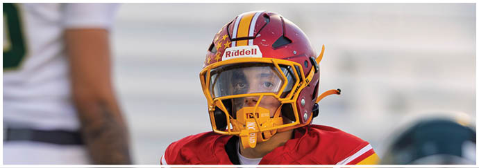 A football player in a white jersey with a red stripe is running with a football. Description generated by AI