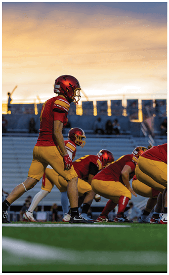 Two football players wearing white uniforms with red and yellow stripes. Description generated by AI