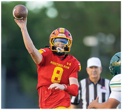 A football player wearing a white jersey with the number 21 on it catching a football. Description generated by AI