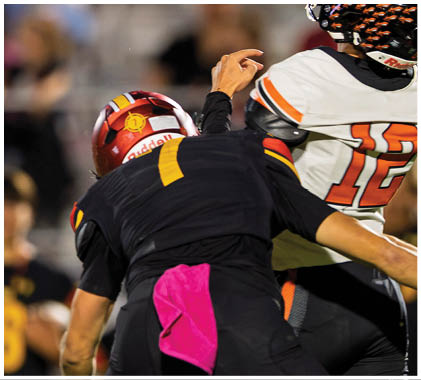 A football player wearing a white jersey with the number 21 on it catching a football. Description generated by AI