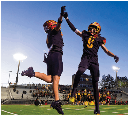 A group of football players running on a field. Description generated by AI