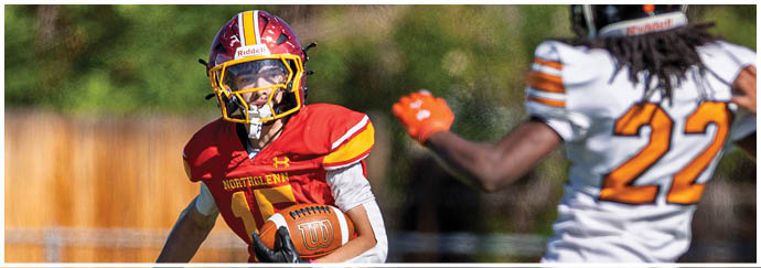 A football player in a white jersey with a red stripe is running with a football. Description generated by AI