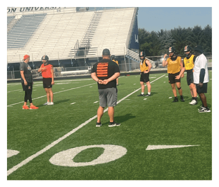 A man in a black jersey is running on a field with a football in his hand. AI generated content