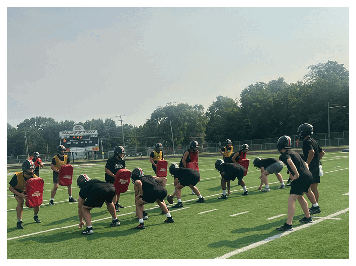 A group of football players on a field, one of them is running with a football. AI generated content