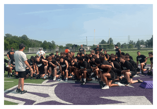 A group of people are kneeling on a field, possibly in a football game. AI generated content