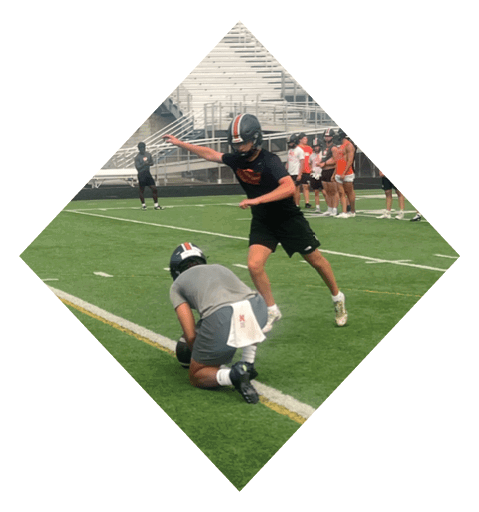 A football player wearing a black jersey with the number 10 sits on the ground with a football helmet on the ground next to him. AI generated content