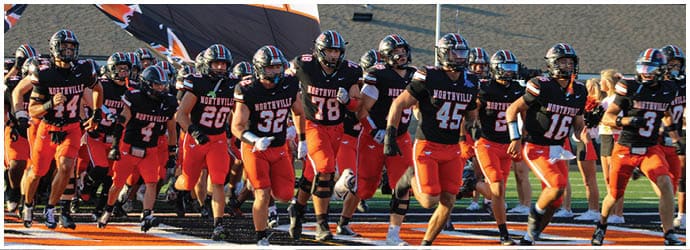 A group of football players on a field. Description generated by AI