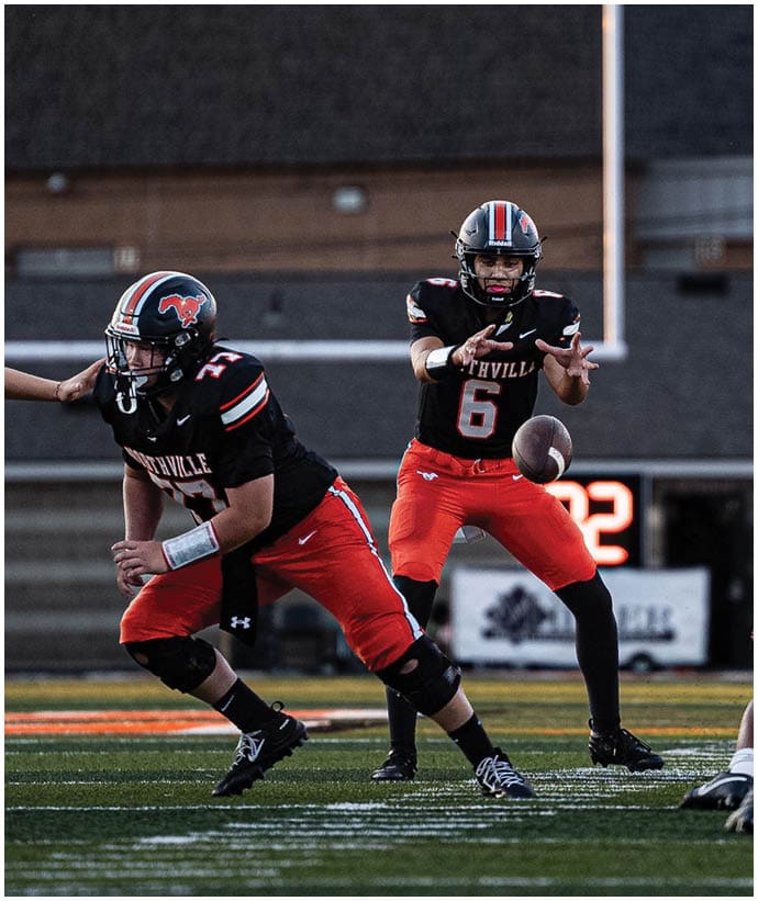 A group of football players wearing black and white uniforms. Description generated by AI