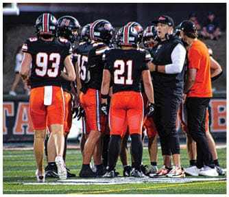 A group of football players wearing black and white uniforms. Description generated by AI